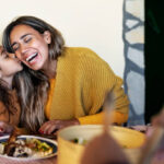 Happy Hispanic mother having tender moment with daughter while dining together with family - Parents love concept